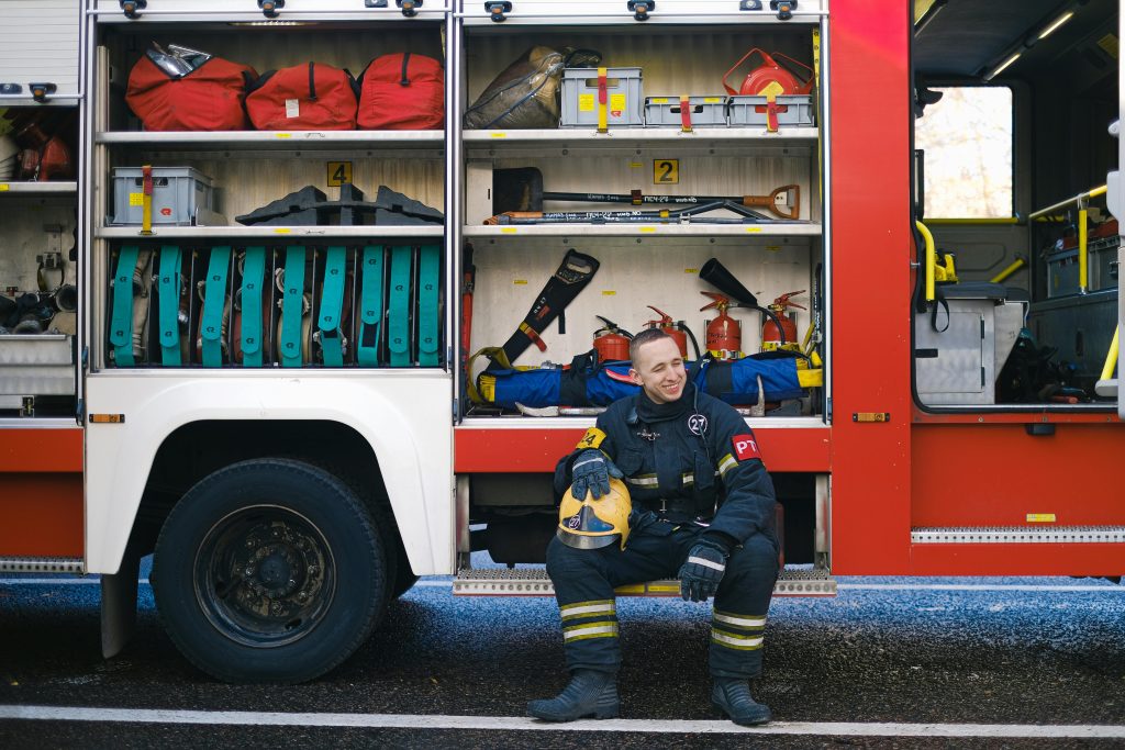 Fire fighter sitting next to truck.
